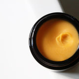 Among the Flowers Gold Balancing Face Balm open jar from above showing the golden balm texture