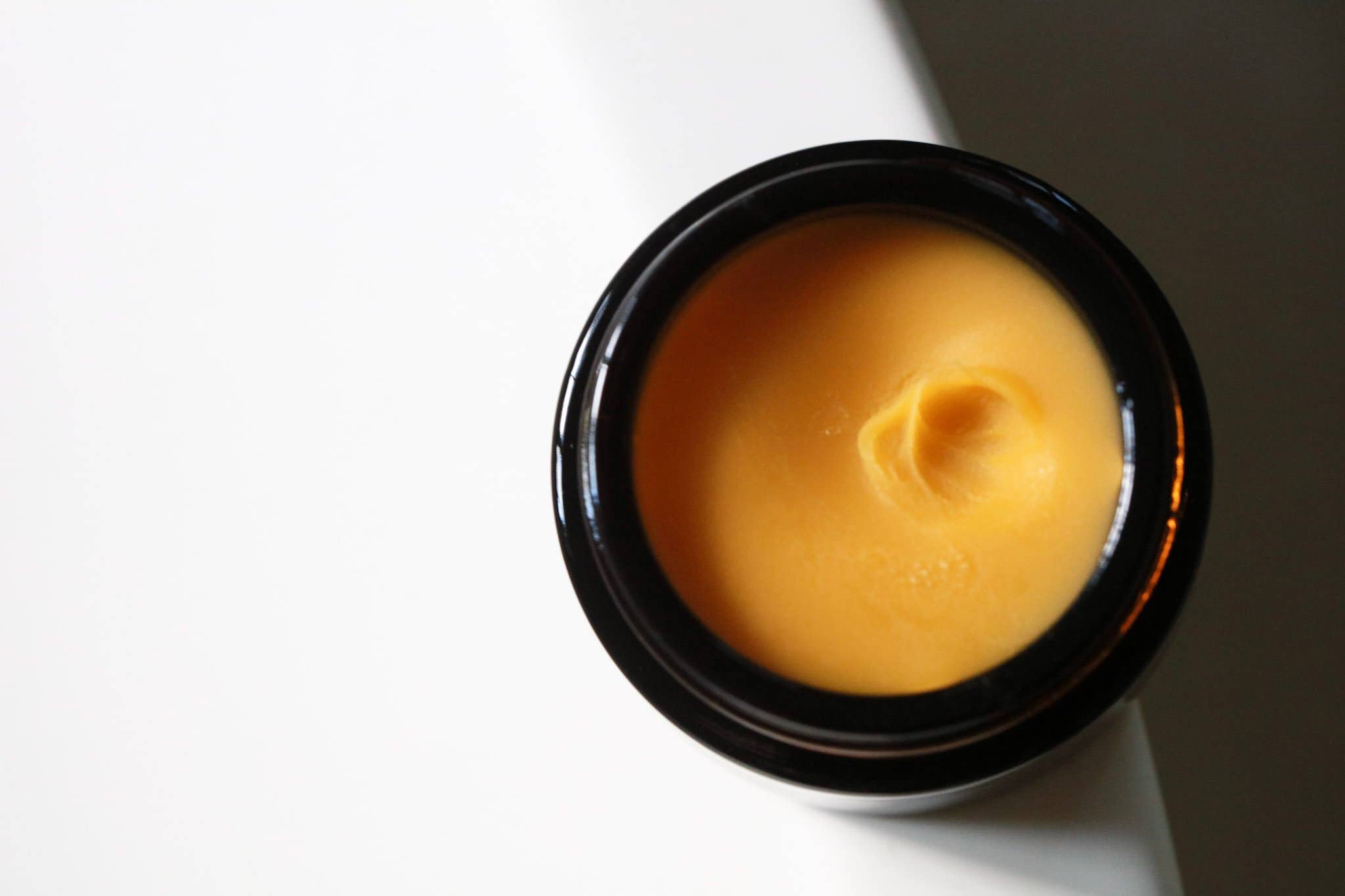 Among the Flowers Gold Balancing Face Balm open jar from above showing the golden balm texture