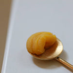 Gold spoon holding a scoop of golden Among the Flowers Gold Balancing Face Balm