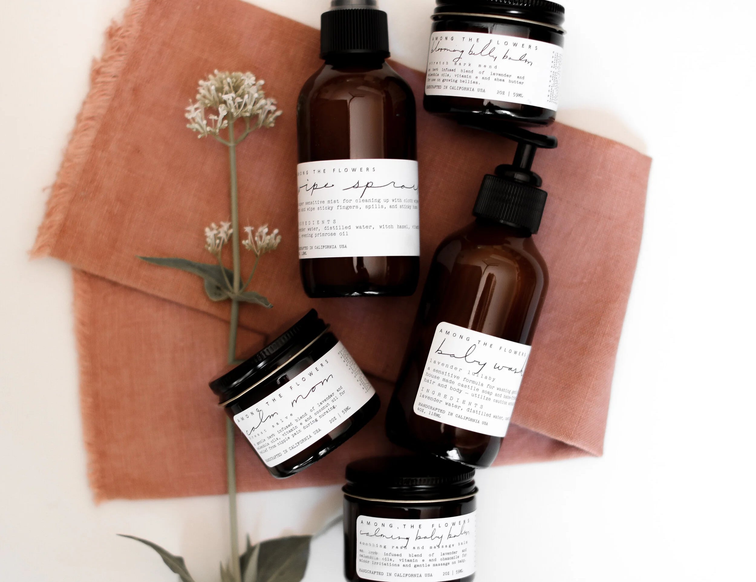 Among the Flowers Lavender Lullaby Baby Wash with other amber-bottle baby products on a rust linen cloth