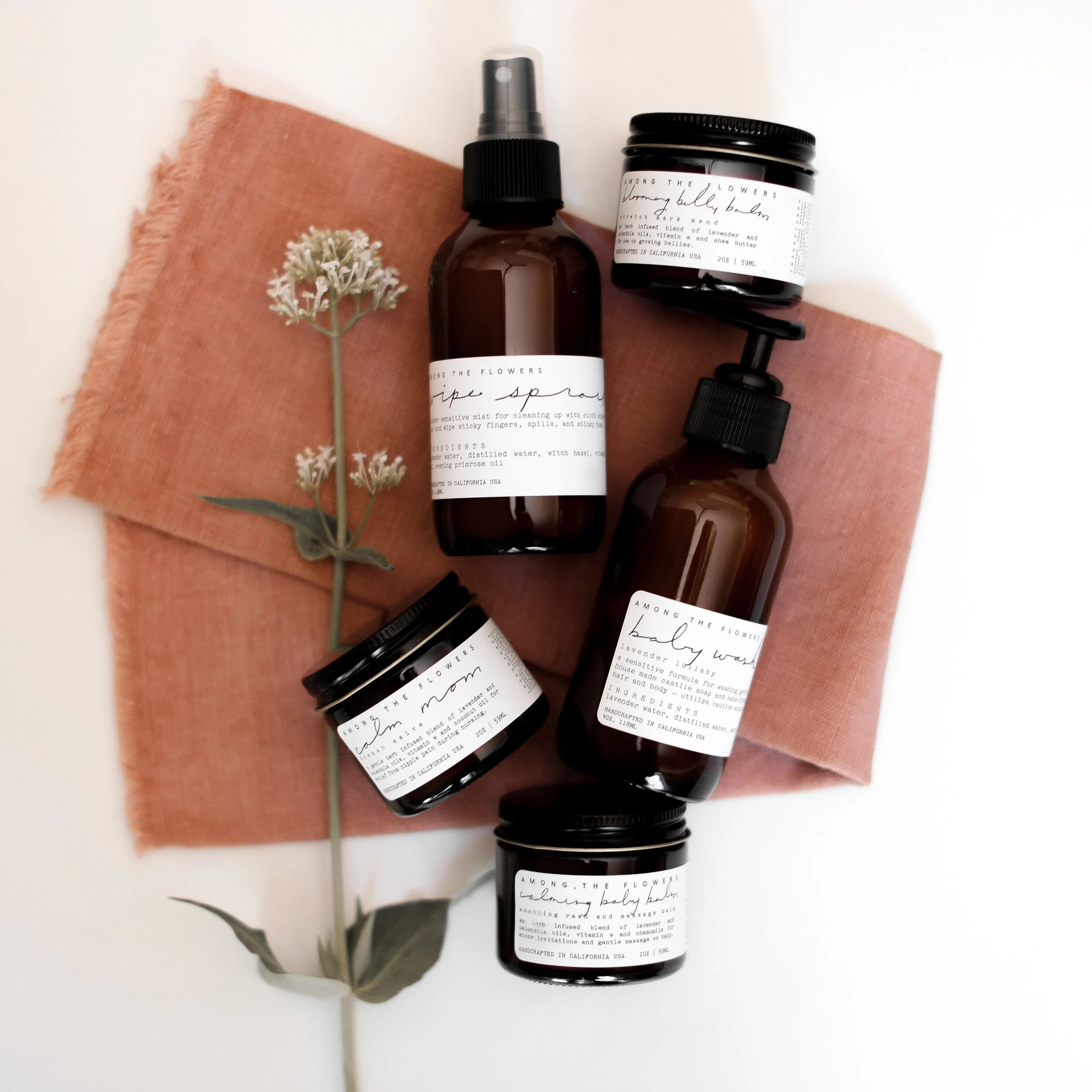Among the Flowers Lavender Lullaby Baby Wash with other amber-bottle baby products on a rust linen cloth