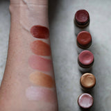 Among the Flowers Lip and Cheek Tint shades swatched on an arm with the open tubes beside