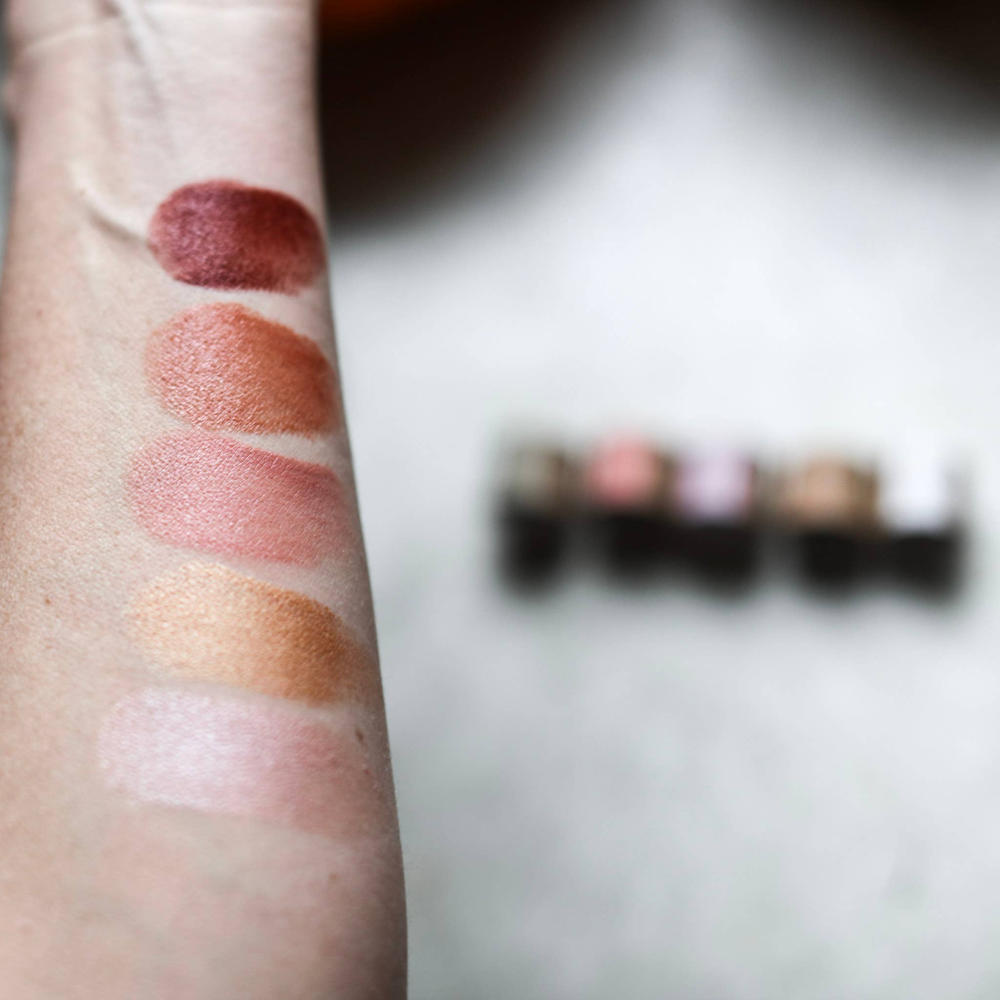 Among the Flowers Lip and Cheek Tint shades swatched on an arm beside the tubes