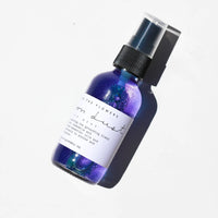 Among the Flowers Moon Dust Pillow Mist in a purple glass spray bottle