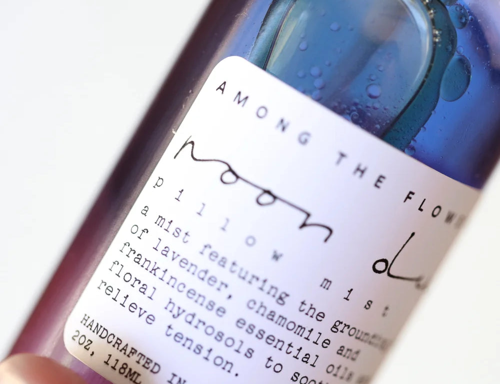 Close-up of the Among the Flowers Moon Dust Pillow Mist label on the purple bottle