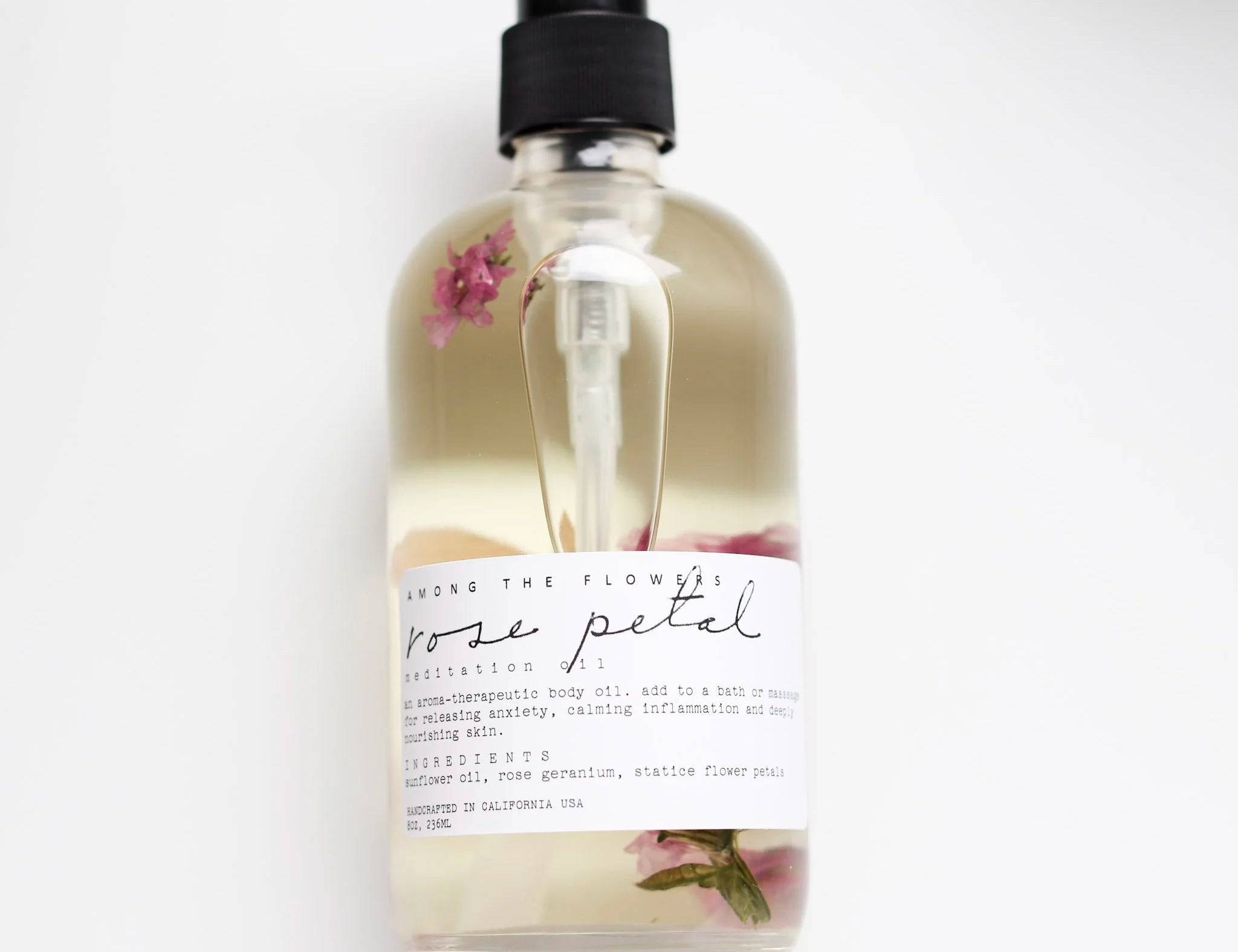 Among the Flowers Rose Petal Meditation Oil in a clear pump bottle with rose petals inside
