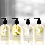 Among the Flowers Meditation Oils in four scents lined up in clear pump bottles by a window