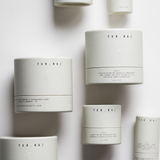 Among the Flowers Tallow Body Cream jars in white cylinder packaging scattered from above