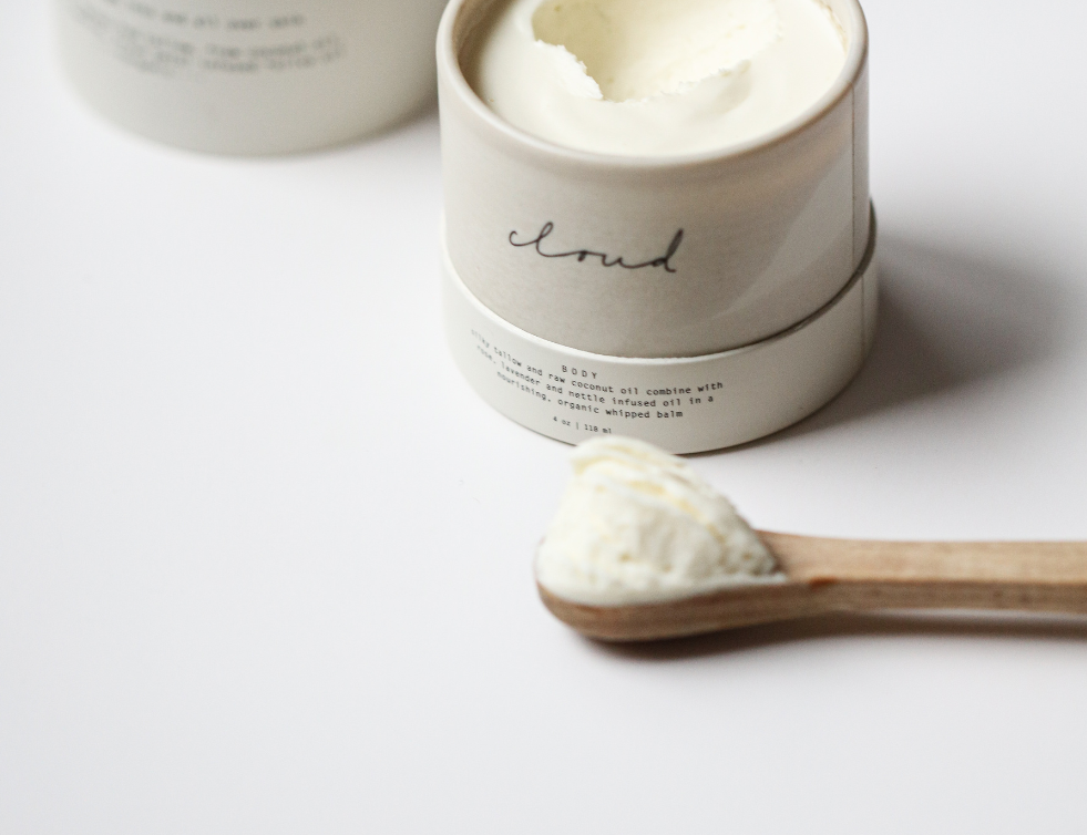 Among the Flowers Tallow Body Cream in an open white jar with a wooden spoon of cream