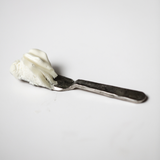 Small spatula holding a scoop of Among the Flowers Tallow Body Cream