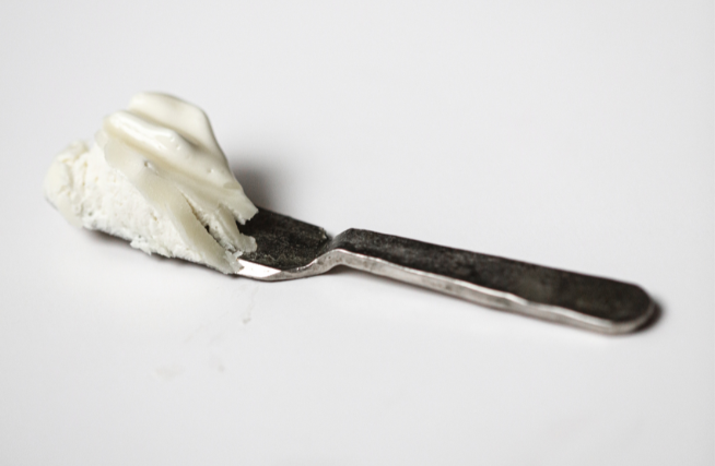 Small spatula holding a scoop of Among the Flowers Tallow Body Cream