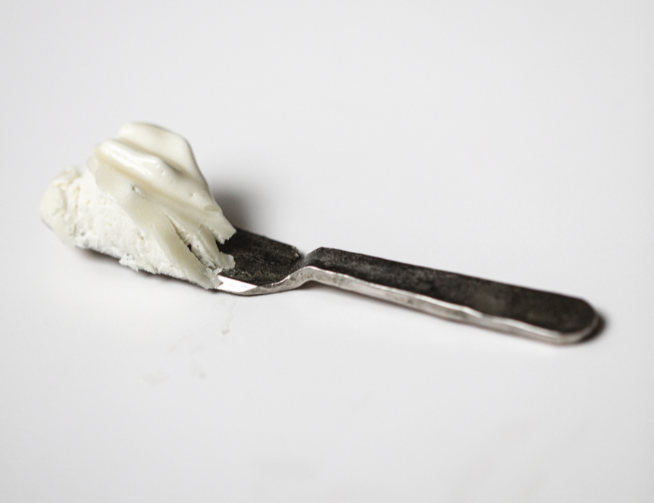Small spatula holding a scoop of Among the Flowers Tallow Body Cream