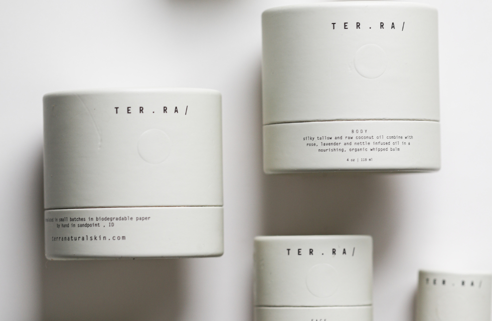 Among the Flowers Tallow Face Cream jars in white cylinder packaging scattered from above