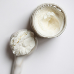 Among the Flowers Tallow Face Cream open jar with a wooden spoon of whipped cream, from above