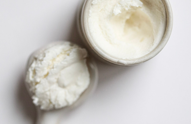 Among the Flowers Tallow Face Cream open jar with a wooden spoon of whipped cream, from above