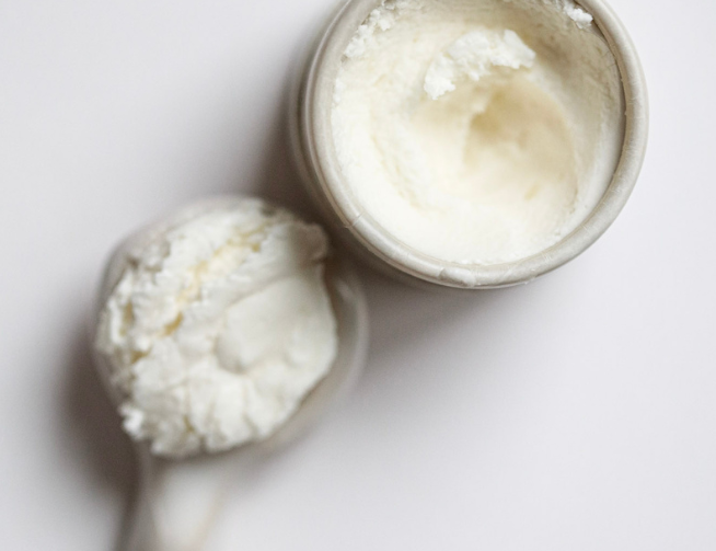 Among the Flowers Tallow Face Cream open jar with a wooden spoon of whipped cream, from above