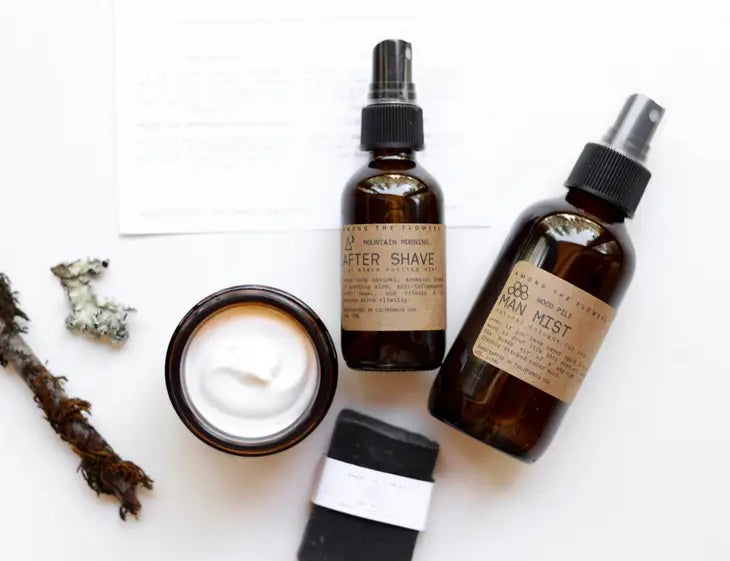 Among the Flowers Wild Man Kit contents laid out: after shave, mist, open balm jar and charcoal soap