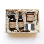 Among the Flowers Wild Man Kit, amber bottles, a jar and a black soap bar in a wooden box with straw