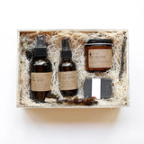 Among the Flowers Wild Man Kit, amber bottles, a jar and a black soap bar in a wooden box with straw