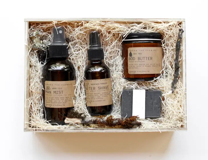 Among the Flowers Wild Man Kit, amber bottles, a jar and a black soap bar in a wooden box with straw