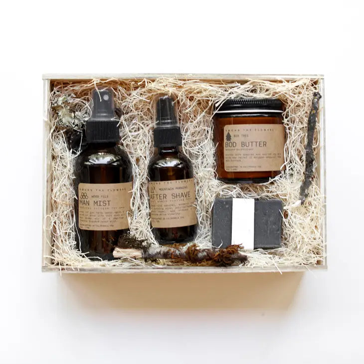 Among the Flowers Wild Man Kit, amber bottles, a jar and a black soap bar in a wooden box with straw