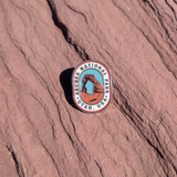 Oval Arches National Park Utah USA enamel pin with Delicate Arch against a blue sky, lying on red sandstone in Moab, Utah.