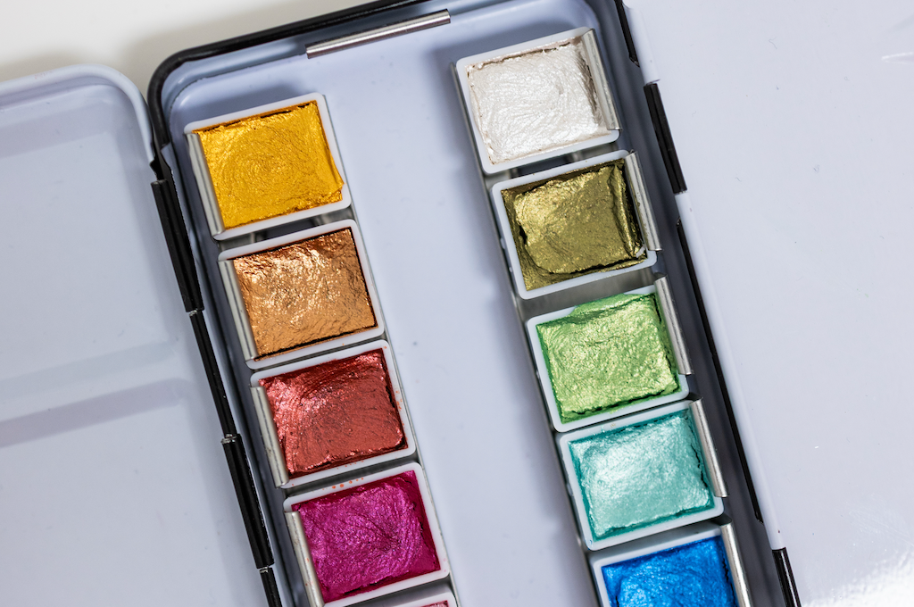 Bailey Rae Studio 12 Color Travel Metallic Watercolor Paint Palette, close-up of metallic gold, green, magenta, teal and blue pans in the open tin