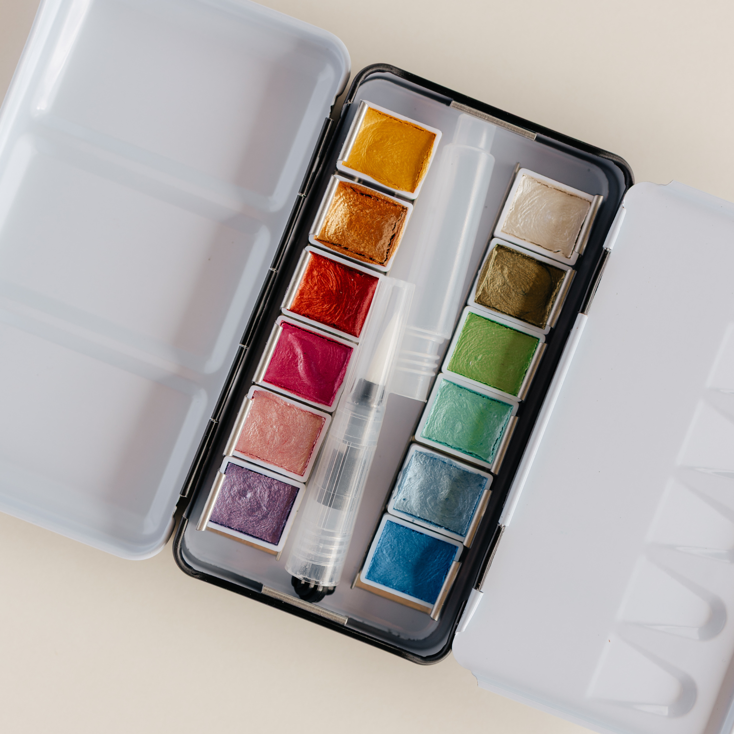 Bailey Rae Studio 12 Color Travel Metallic Watercolor Paint Palette, open tin showing twelve shimmering metallic watercolor pans and a brush