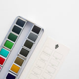 Bailey Rae Studio 24 Color Watercolor Paint Palette, close-up of green, teal, brown and grey pans beside the swatch chart card