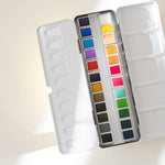 Bailey Rae Studio 24 Color Watercolor Paint Palette, open tin with mixing wells and twenty-four colorful pans in soft light on white