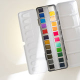 Bailey Rae Studio 24 Color Watercolor Paint Palette, open tin with mixing wells and twenty-four colorful pans in soft light on white