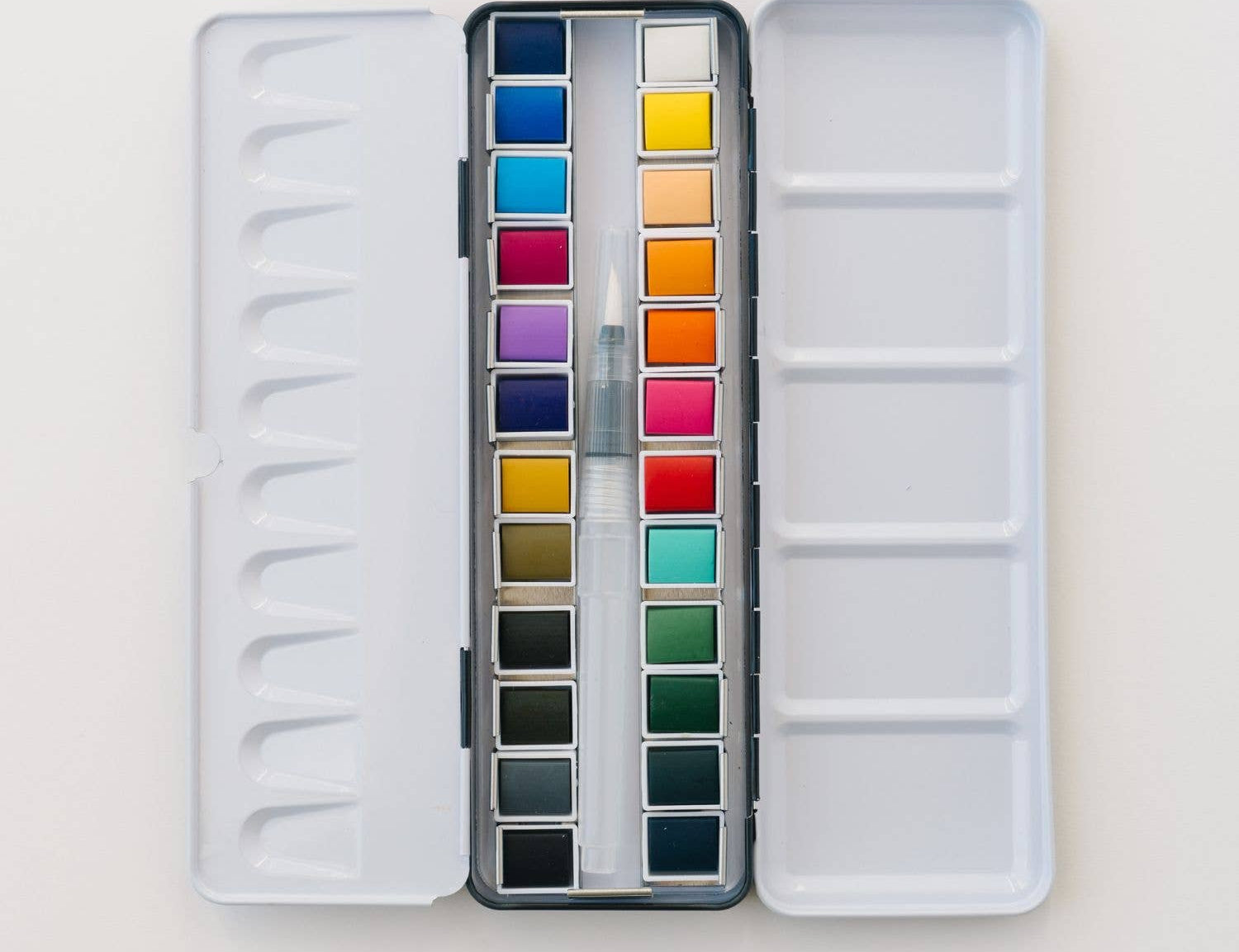 Bailey Rae Studio 24 Color Watercolor Paint Palette, open silver tin with two rows of twelve watercolor pans and a water brush, on white