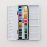 Bailey Rae Studio 24 Color Watercolor Paint Palette, open silver tin with two rows of twelve watercolor pans and a water brush, on white