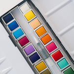 Bailey Rae Studio 24 Color Watercolor Paint Palette, close-up of bright yellow, orange, red, pink and blue watercolor pans with the water brush