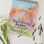 Bailey Rae Studio National Parks Watercoloring Book with brushes and white flowers
