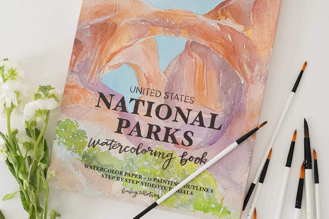 Bailey Rae Studio National Parks Watercoloring Book with brushes and white flowers