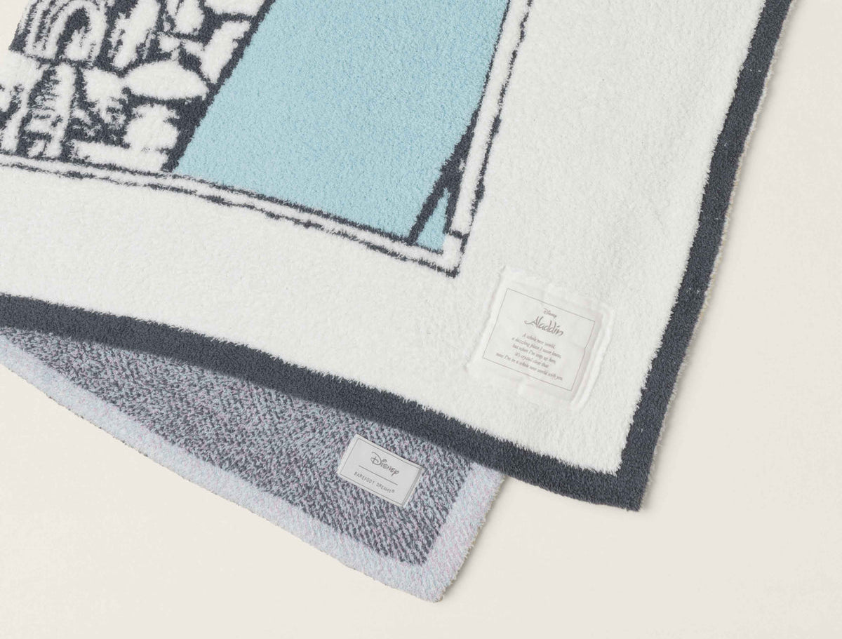 Close-up of the teal and navy knit detail and gray reverse on the Barefoot Dreams Cozy Disney Princess Blanket in Jasmine