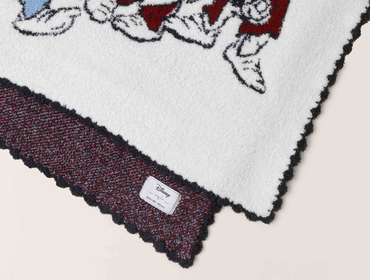 Close-up of the scalloped edge and burgundy reverse on the Barefoot Dreams Cozy Disney Princess Blanket in Snow White