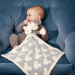 Baby in a blue chair cuddling the Barefoot Dreams Disney Blanket Buddie in Vintage Mickey Mouse