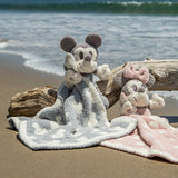 Barefoot Dreams Disney Blanket Buddies in Vintage Mickey and Vintage Minnie on a beach beside driftwood