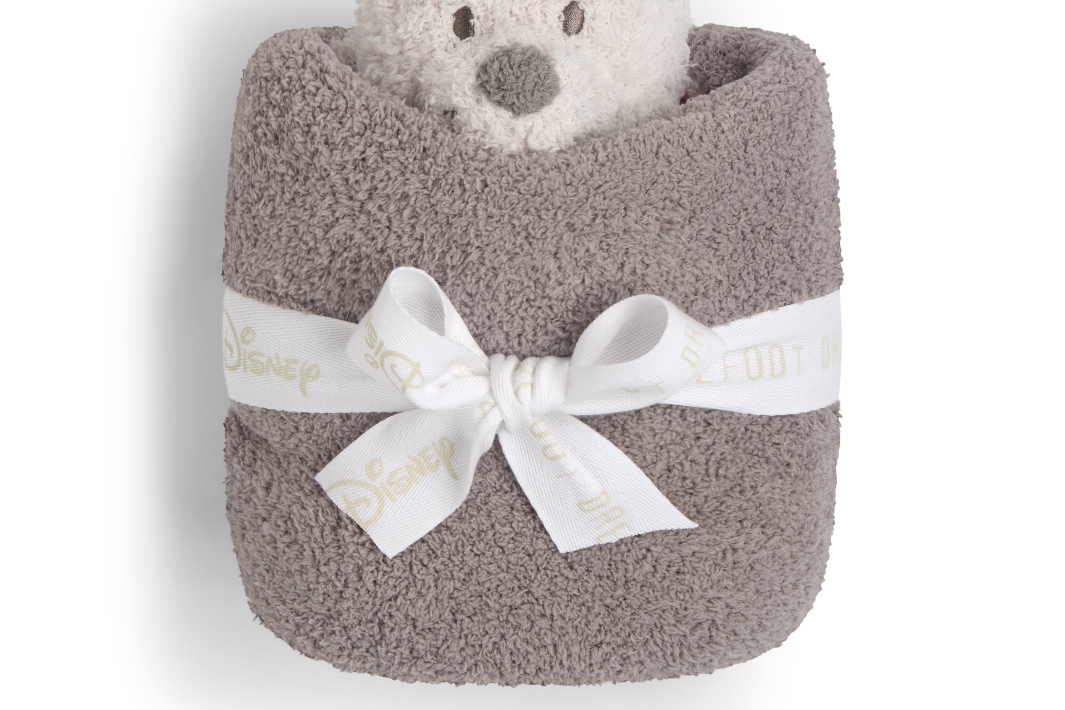 Barefoot Dreams Disney Blanket Buddie in Winnie the Pooh rolled in a taupe blanket and tied with a ribbon