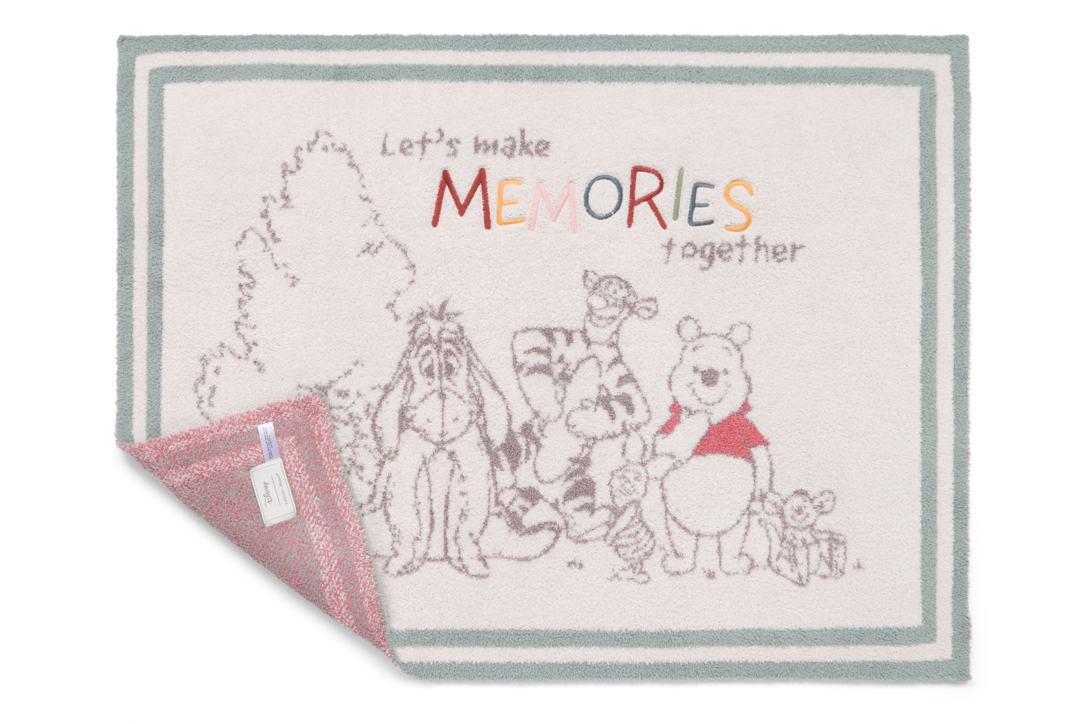 Barefoot Dreams Disney Stroller Blanket in Winnie the Pooh with a corner turned to show the pink reverse