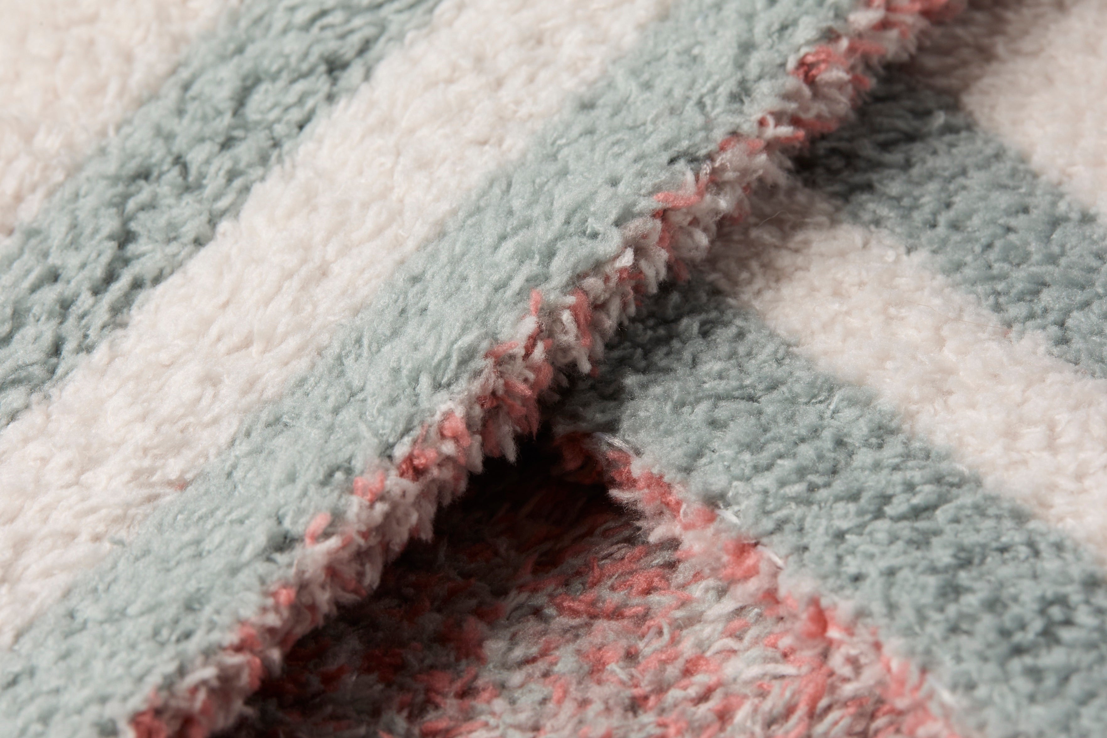 Close-up of the sage and pink knit edge on the Barefoot Dreams Disney Stroller Blanket in Winnie the Pooh