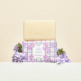 Beekman 1802 Bar Soap in Lilac Dream unwrapped on its box with fresh lilac blooms