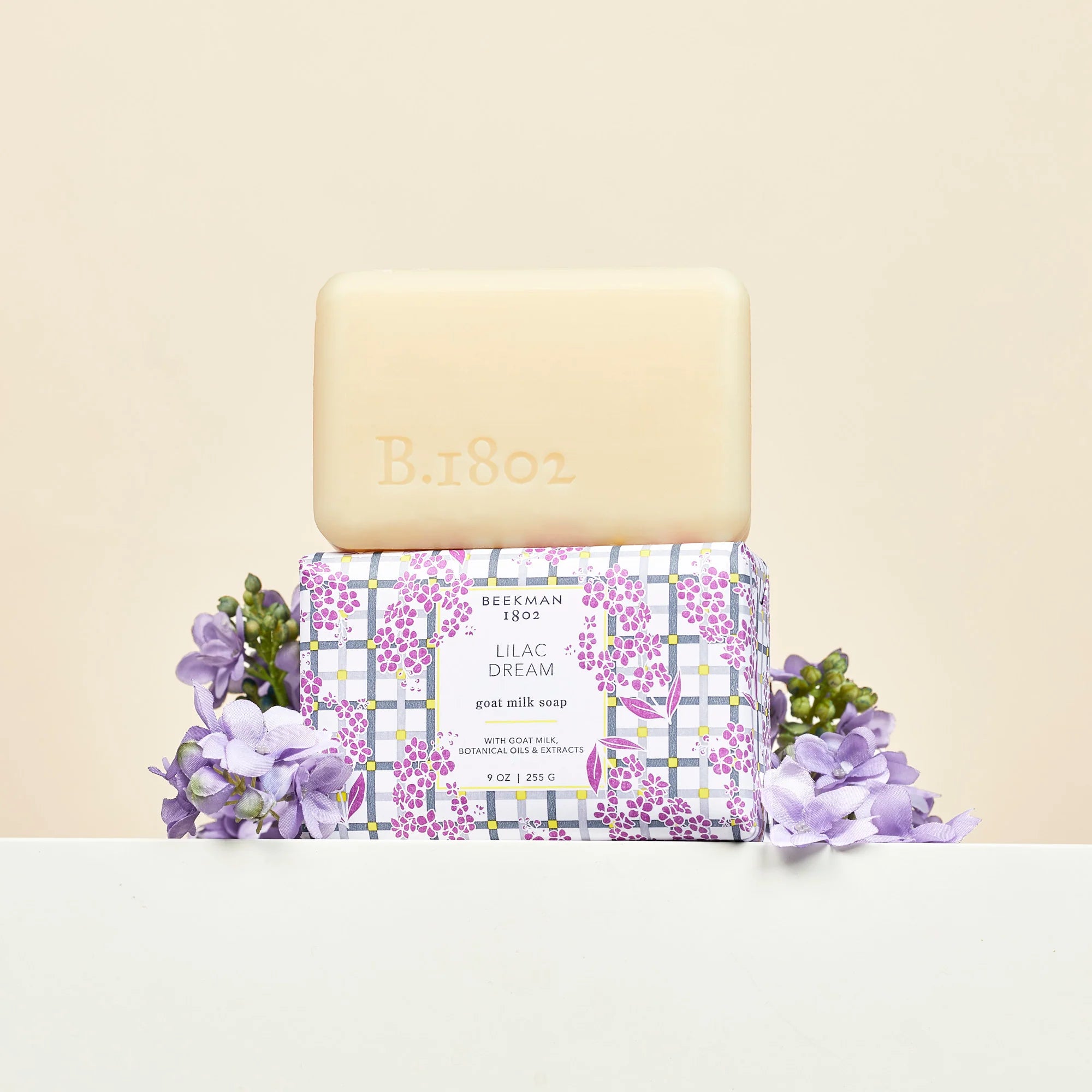 Beekman 1802 Bar Soap in Lilac Dream unwrapped on its box with fresh lilac blooms