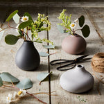 Blomus Nona 3 Vase Set holding eucalyptus and daisies on a rustic wooden table