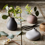 Blomus Nona 3 Vase Set holding eucalyptus and daisies on a rustic wooden table