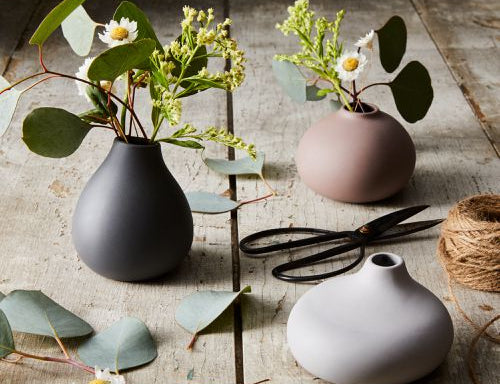 Blomus Nona 3 Vase Set holding eucalyptus and daisies on a rustic wooden table