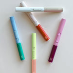 Botanica Flameless Lighters in assorted two-tone colors scattered on a white surface