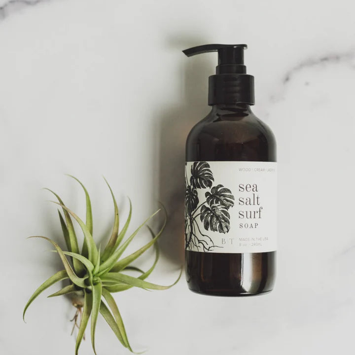 Broken Top Brands Sea Salt Surf Hand Soap bottle with an air plant on marble, from above